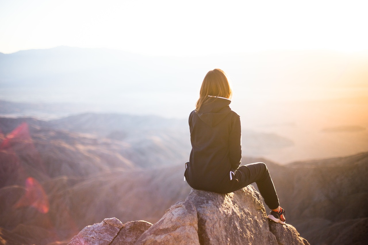 woman on a mountain top looking out, seated